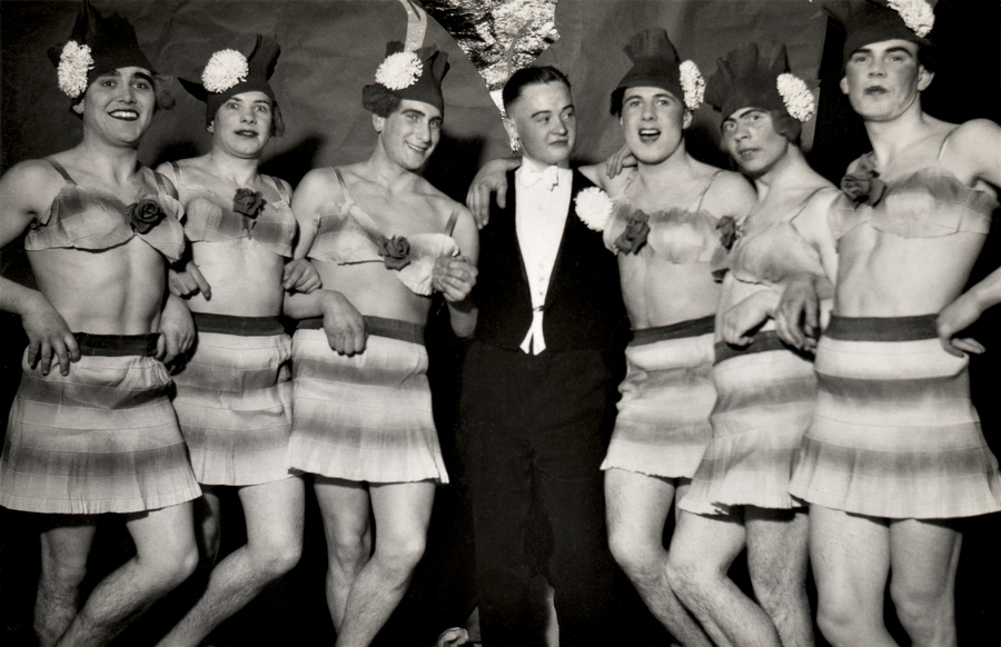 Unidentified photographer, [A tuxedo-wearing man surrounded by six male cross-dressers, with written inscription on verso “Das Ballet von Kompaniefest im Winter 1937/38 (The Kompaniefest Ballet in the Winter of 1937/38)”, Germany], 1937. © 2016 Éditions Textuel – Collection Sébastien Lifshitz